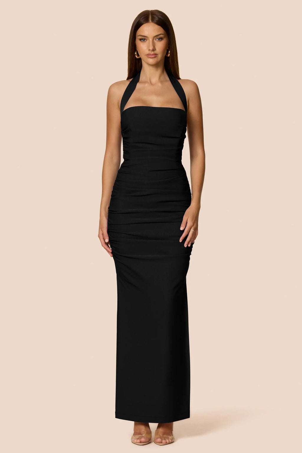 Woman wearing a black halter neck dress against a beige background
