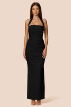 Woman wearing a black halter neck dress against a beige background