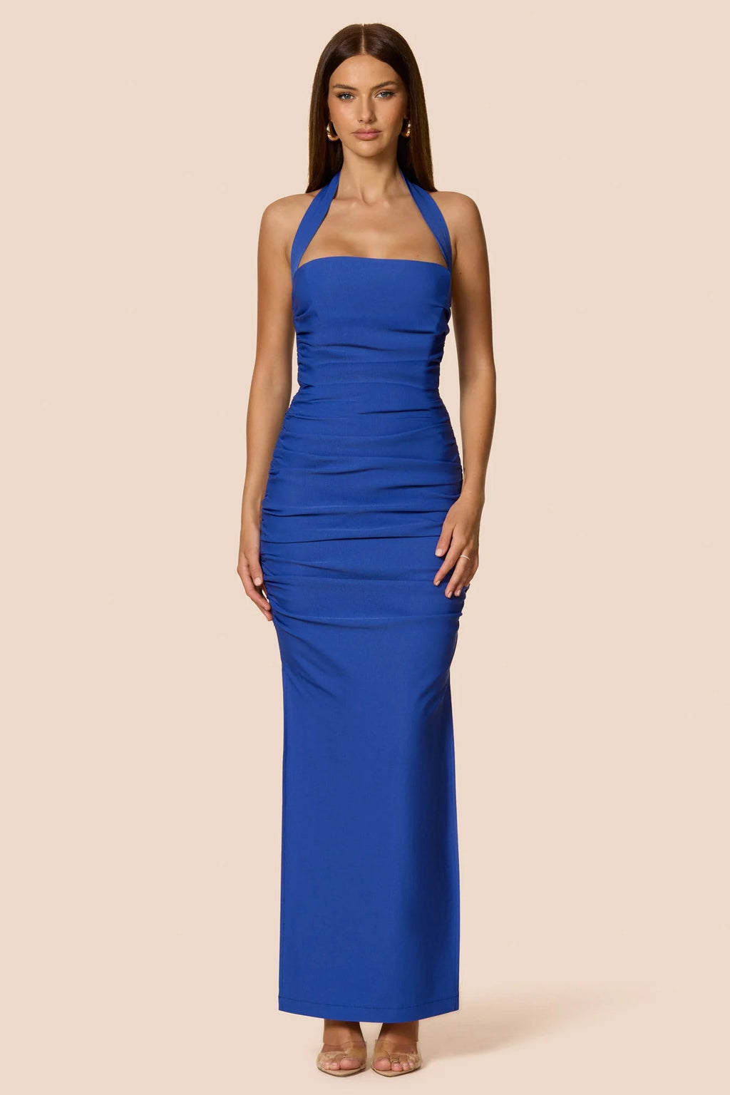 Woman wearing a blue halter neck dress on a beige background
