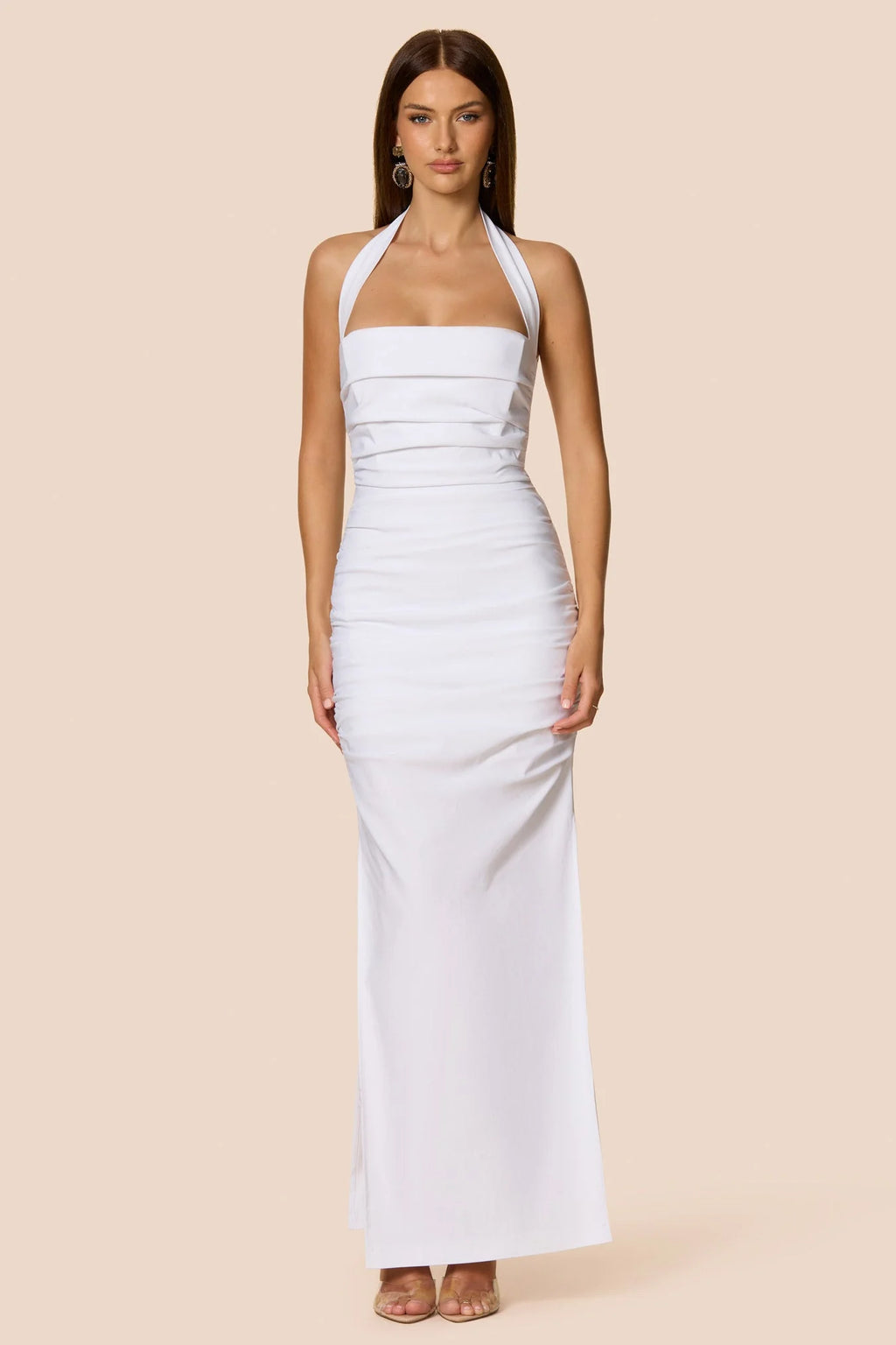 Woman wearing a white halter neck dress against a beige background